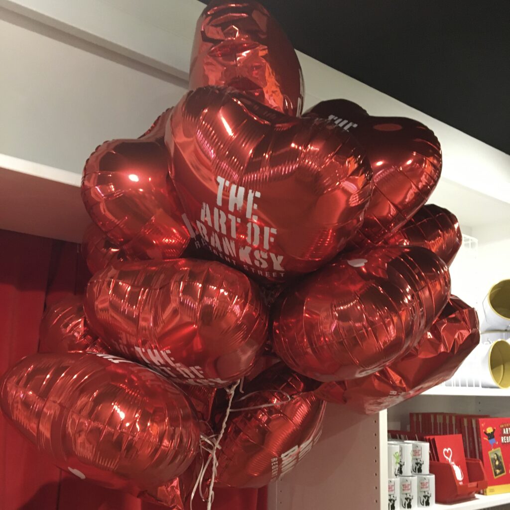 The art of Banksy exhibition in Regent Street showcasing red heart balloons